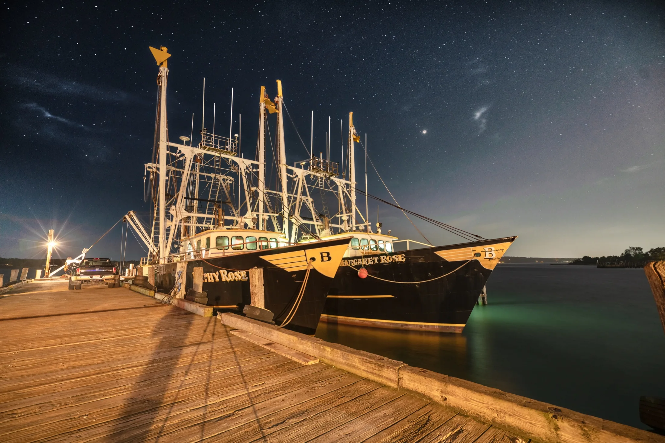 Boats and marina lights in Greenport Harbor at night, photographed by Alexander Aquino